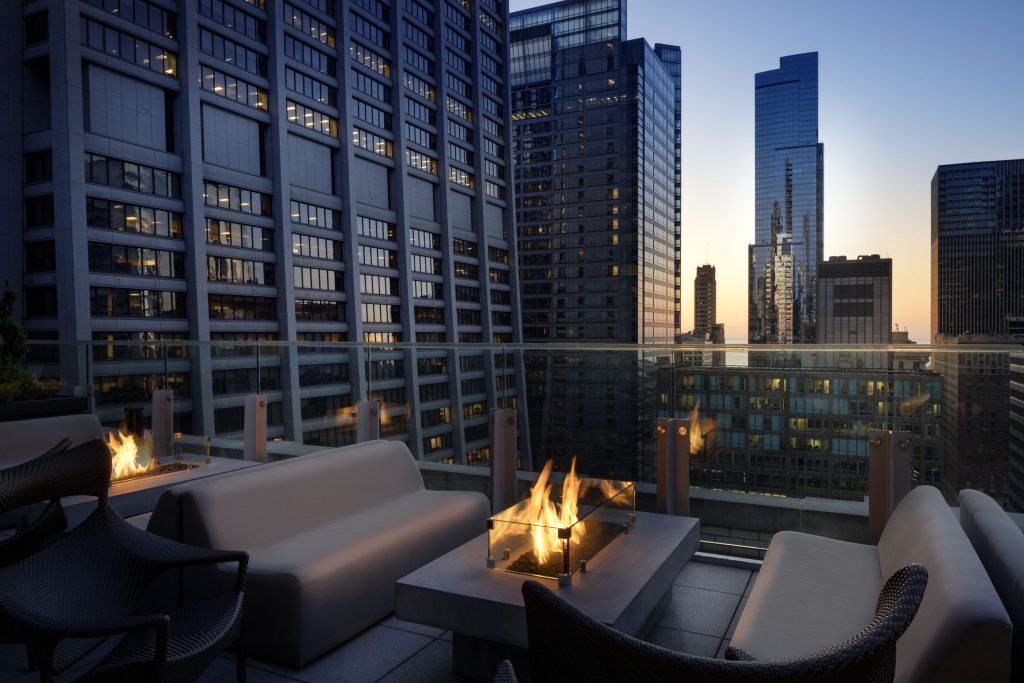 Sunset rooftop lounge at Hyatt Centric The Loop with fire pit and city skyline.