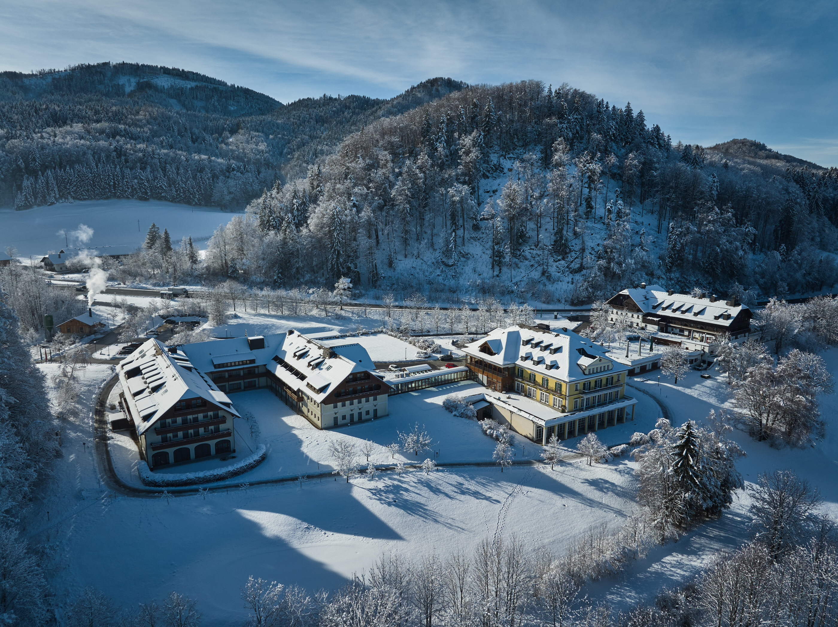 Hotel complex nestled against wooded hillside in full winter snow