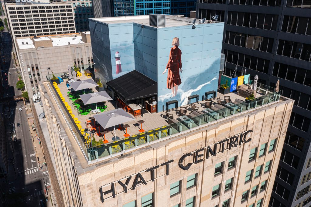 Elevated rooftop view of Hyatt Centric with seating area and large mural.