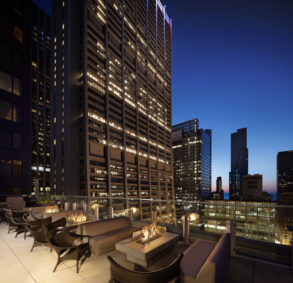 Nighttime rooftop lounge at Hyatt Centric surrounded by high-rise lighting. • Title: