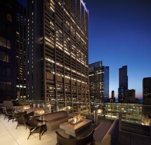 Nighttime rooftop lounge at Hyatt Centric surrounded by high-rise lighting. • Title: