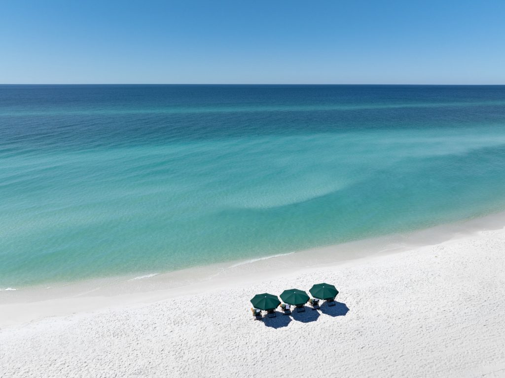 Overhead view of grouped umbrellas on white sand beach in Florida.