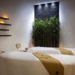 Spa treatment room at Sheraton Muscat with green wall and accent lighting.