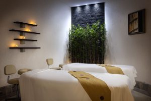 Spa treatment room at Sheraton Muscat with green wall and accent lighting.