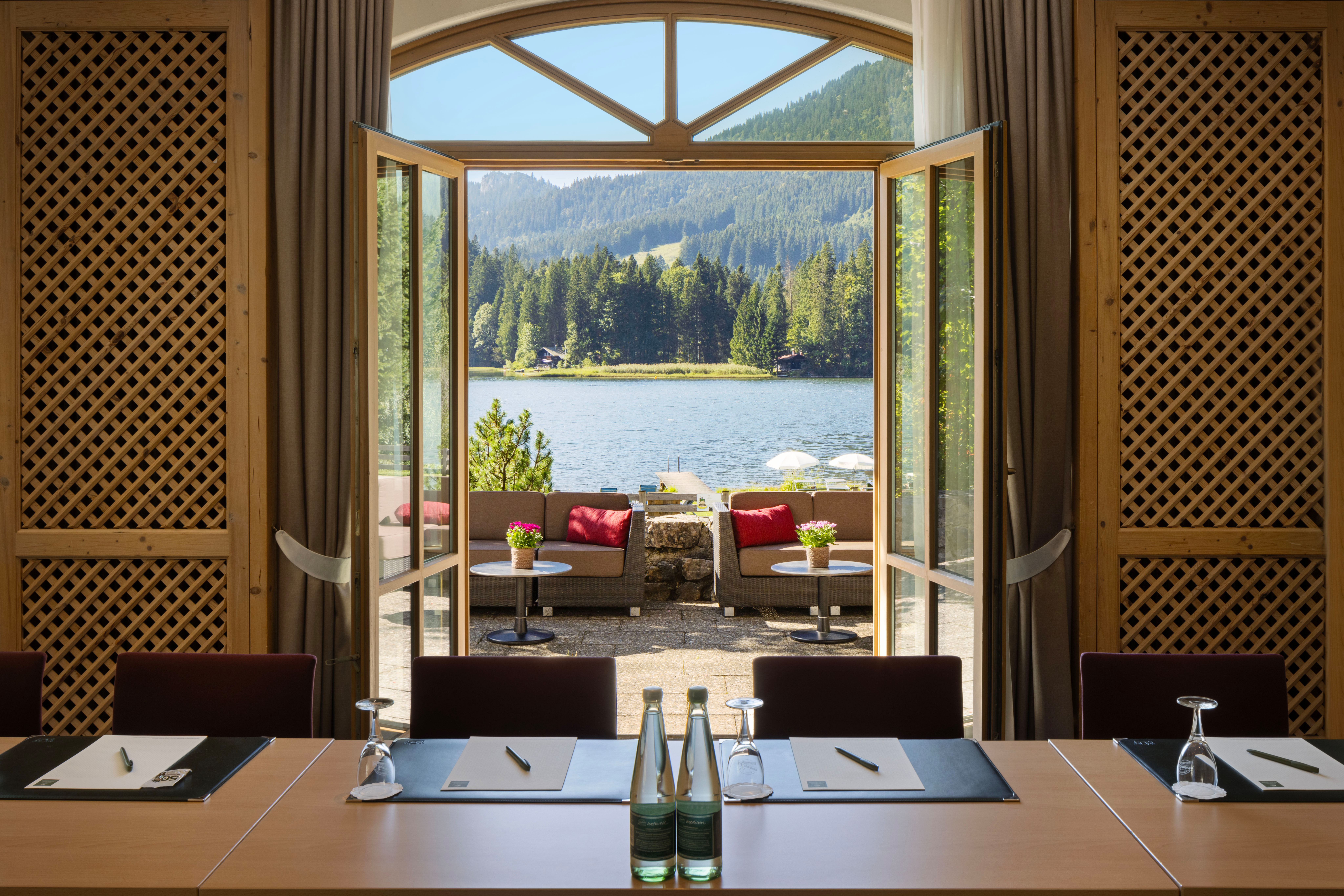 Elegant meeting room with open doors overlooking Spitzingsee lake in the Bavarian Alps