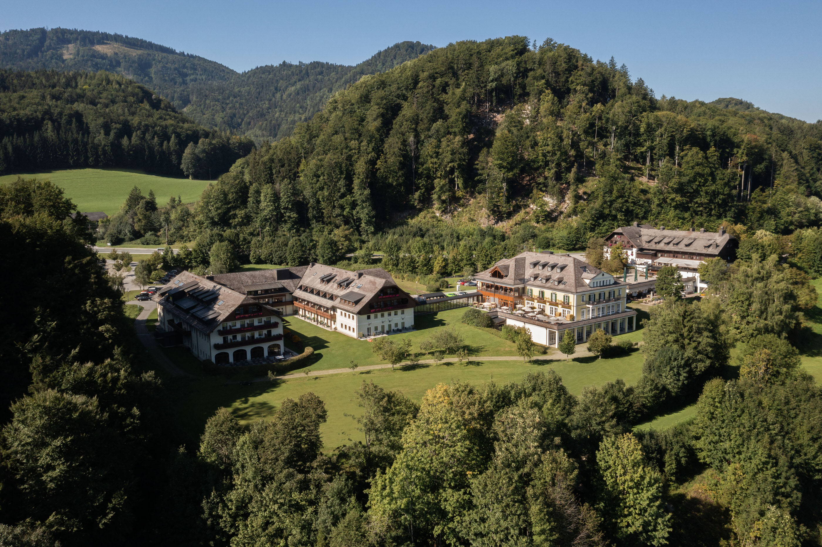 Drone image of hotel complex in green mountain terrain during summer