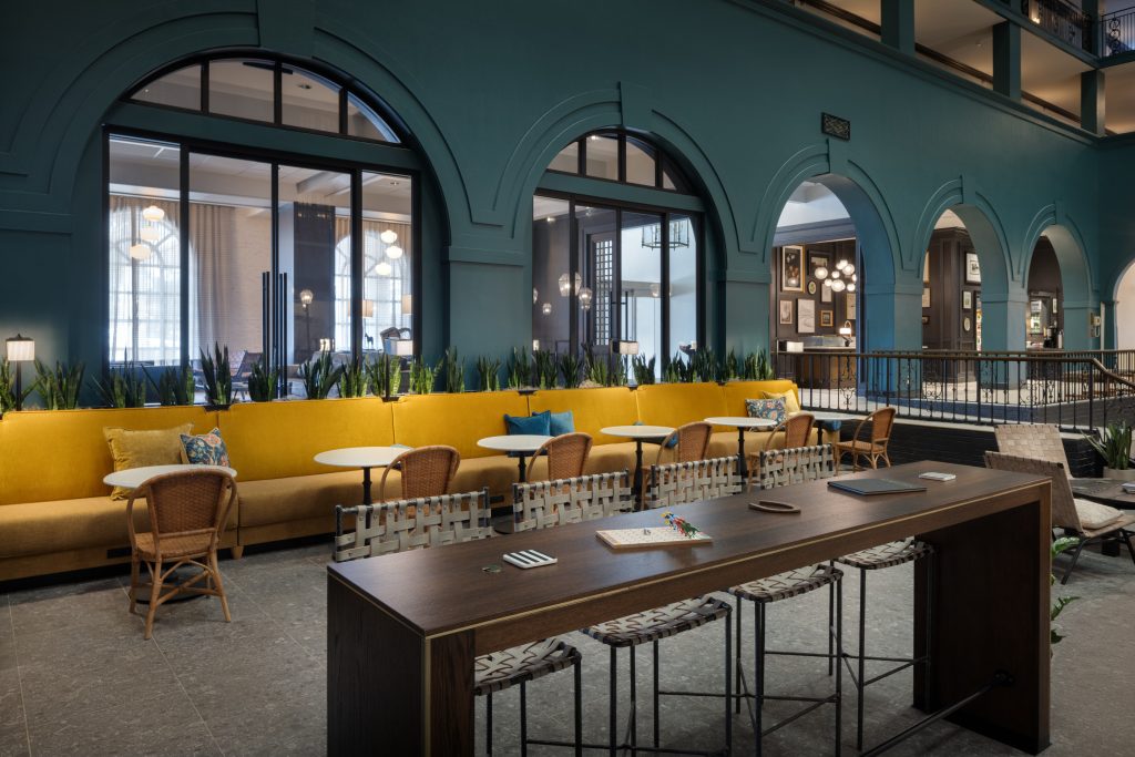Stylish atrium lounge at DoubleTree Lexington with yellow banquette seating and high-top workspace.