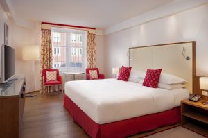 Bright guest room at Sheraton Grand Salzburg with red pillows and traditional decor
