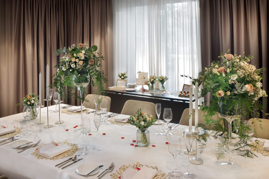 Event dining table with floral centrepiece and dessert table in background at Sheraton Grand Salzburg