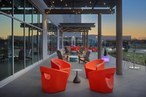 Sunset terrace at Aloft Wichita with red chairs and pond water view