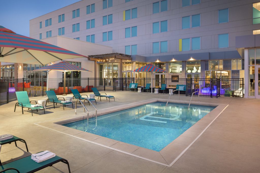 Outdoor pool at Aloft Wichita with loungers and umbrellas.