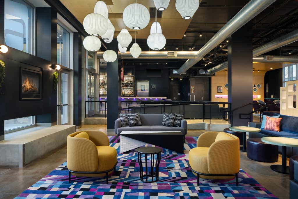 Lobby seating at Aloft Wichita with yellow chairs and patterned rug.
