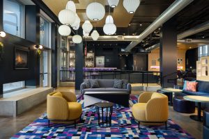 Lobby seating at Aloft Wichita with yellow chairs and patterned rug.