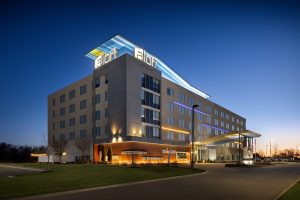 Aloft Wichita hotel exterior at dusk with illuminated signage and clean modern lines.