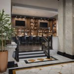 Pennydrop Bar at The Pennywell Hotel St. Louis — heritage marble lobby floor with gold geometric inlay, ornate balustrade, and warm wood back bar