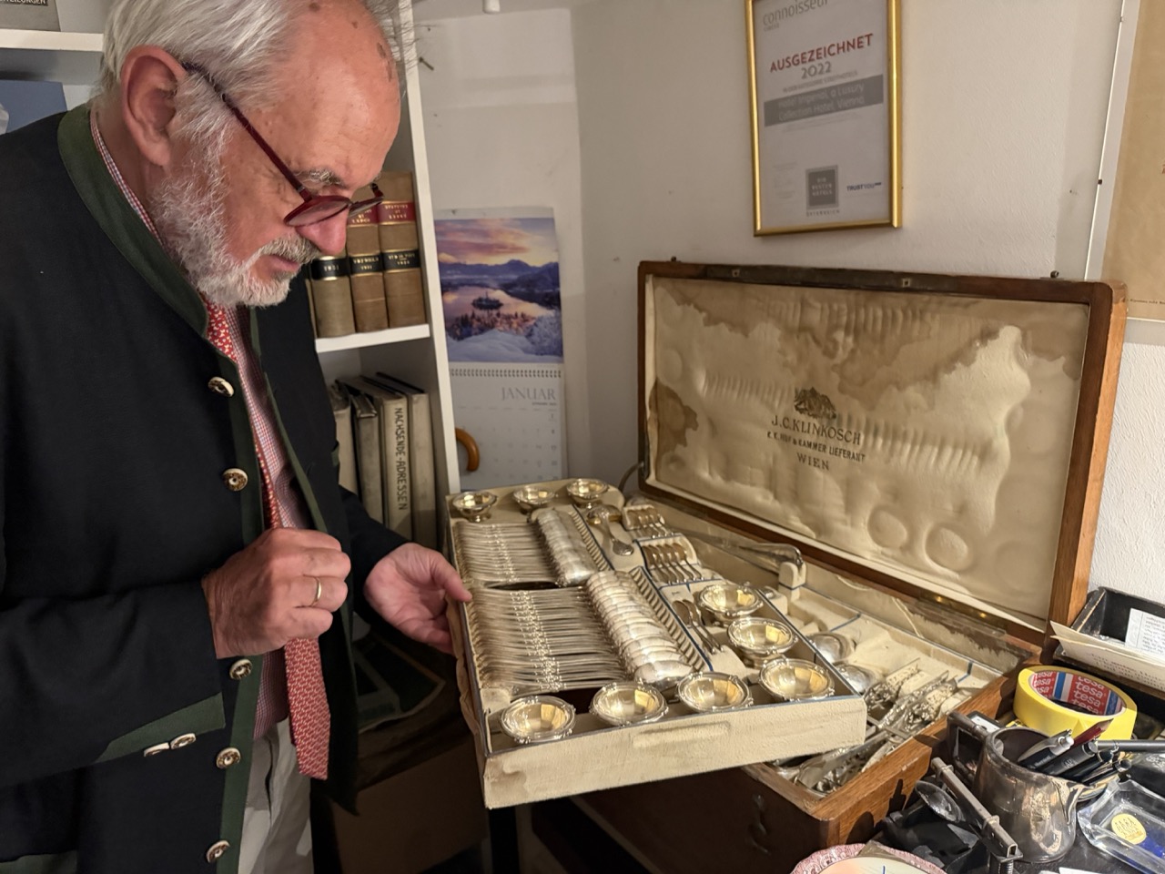 Michael Moser standing beside cutlery in its presentation case in the Hotel Imperial Vienna archive