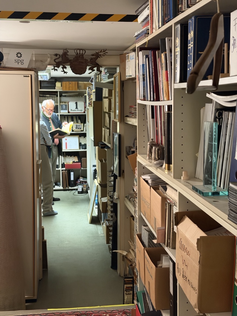 Michael Moser standing among shelves of records and objects in the Hotel Imperial Vienna archive
