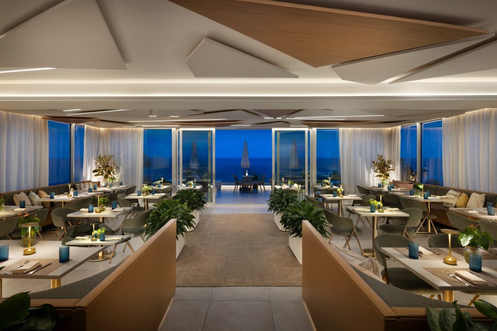 Symmetrical blue-hour view through the MB Hotel rooftop restaurant towards the ocean terrace