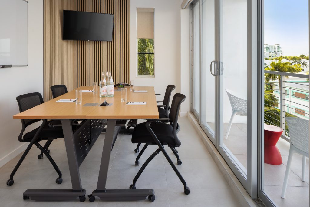 Small MB Hotel Miami Beach meeting room with six chairs, display screen and balcony doors