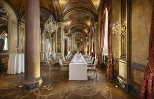 Long formal dining table beneath crystal chandeliers and vaulted ceilings at Hotel Imperial Vienna