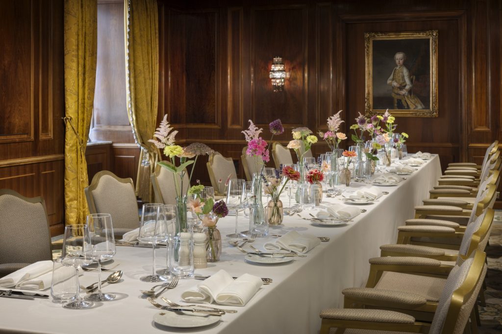 Long flower-filled dining table in a wood-panelled private room at Hotel Imperial Vienna