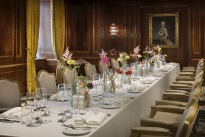 Long flower-filled dining table in a wood-panelled private room at Hotel Imperial Vienna
